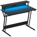 Escritorio gaming Kiel en negro con luces LED RGB encendidas en una sala de juego