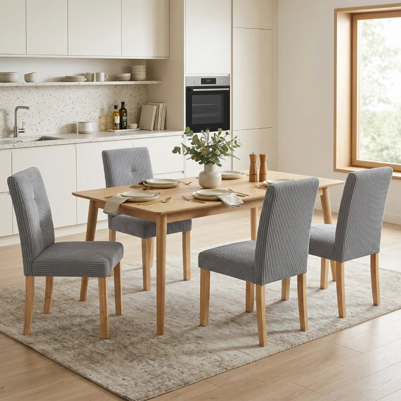 Sillas de comedor tapizadas en pana gris alrededor de una mesa moderna