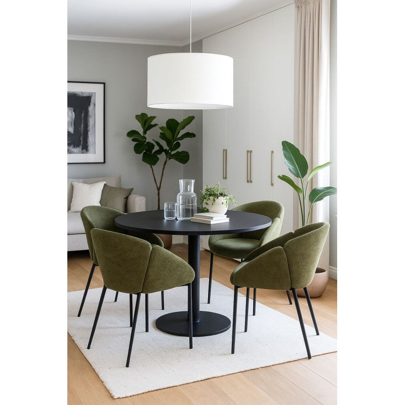 Sillón de chenilla verde en un salón con plantas y luz natural